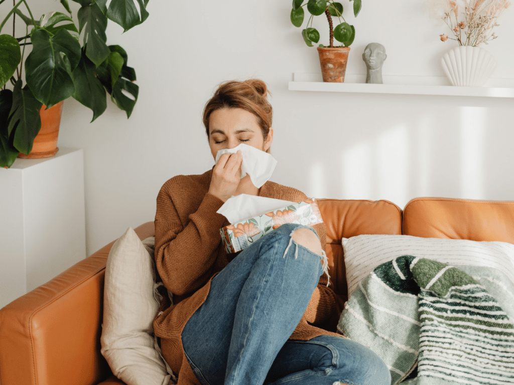 woman with allergies in home using tissues